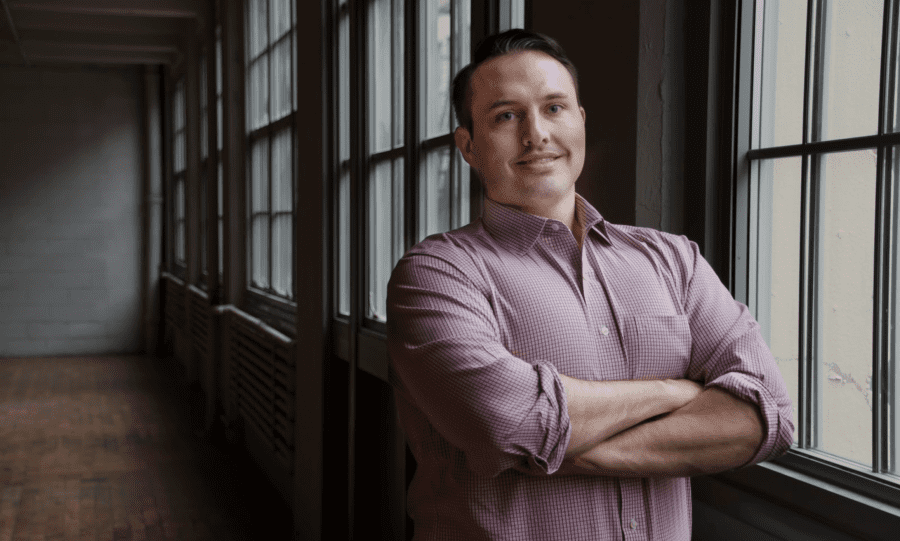 GCA smiling man standing in empty hallway with arms crossed