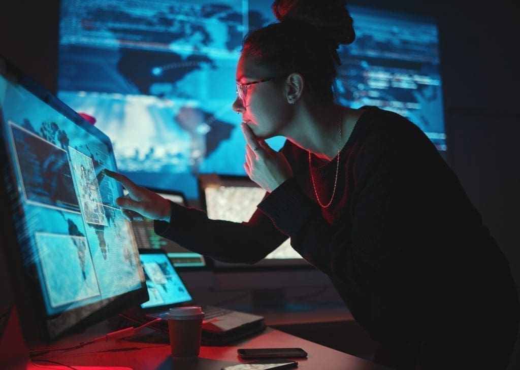 Woman concentrating on computer with screens around her.