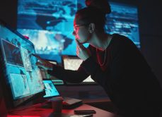 Woman concentrating on computer with screens around her.