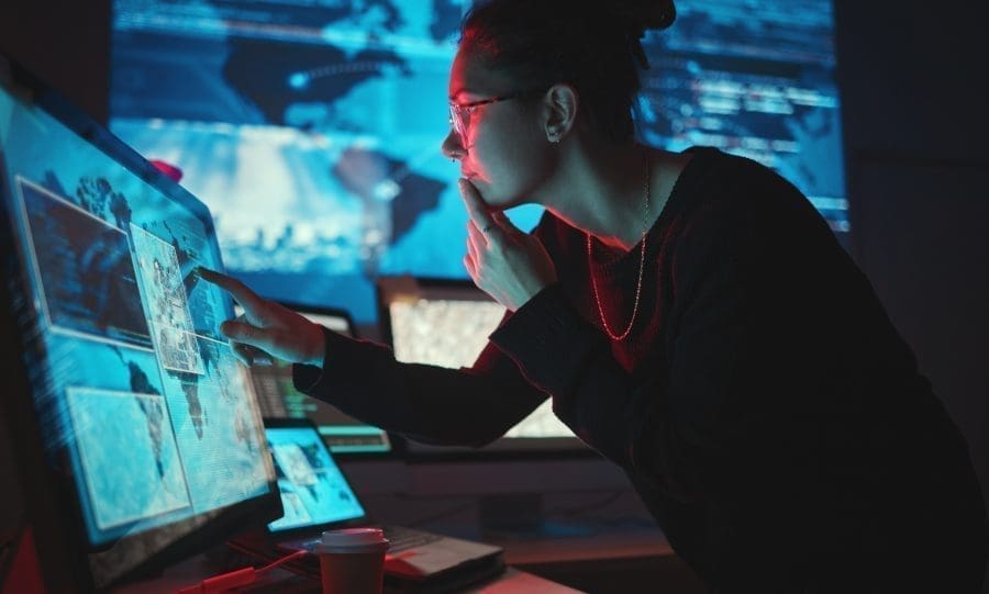 Woman concentrating on computer with screens around her.