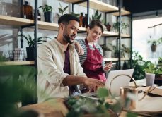 Shop assistants with laptop working in potted plant store, small business concept.
