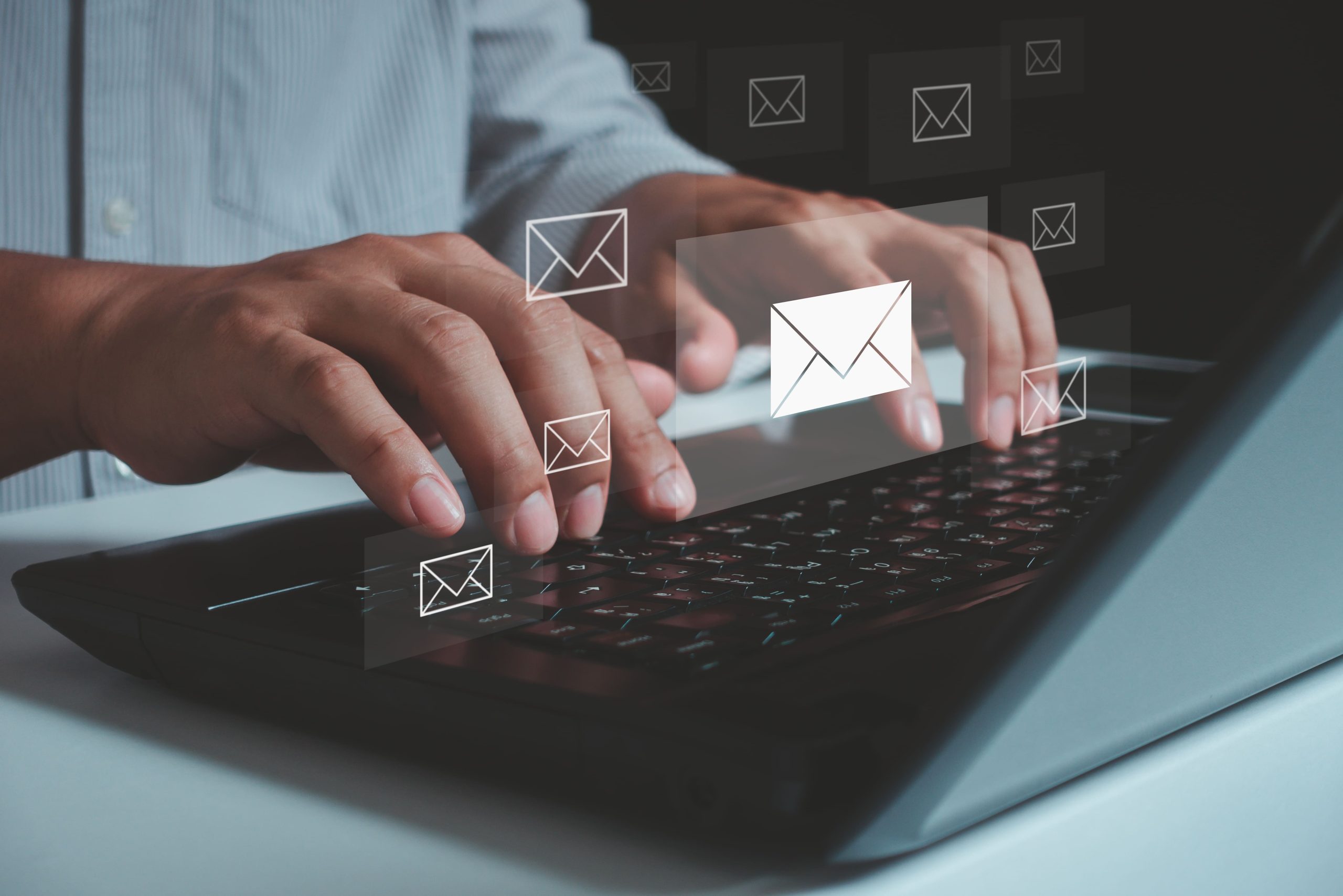 Person typing on a laptop wth email icons overlaid.
