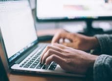Close-up of hands typing on a laptop.