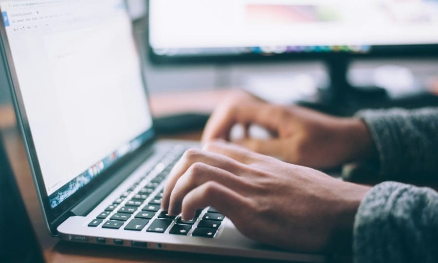 Close-up of hands typing on a laptop.