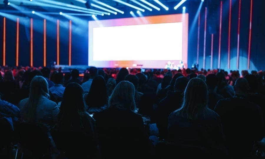 People in audience watching a large stage.