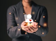 Empathy female manager holding human icon with heart shape over palm hands.