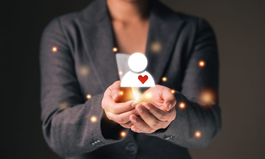 Empathy female manager holding human icon with heart shape over palm hands.