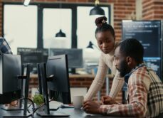 Two people looking at a computer screen on a desk