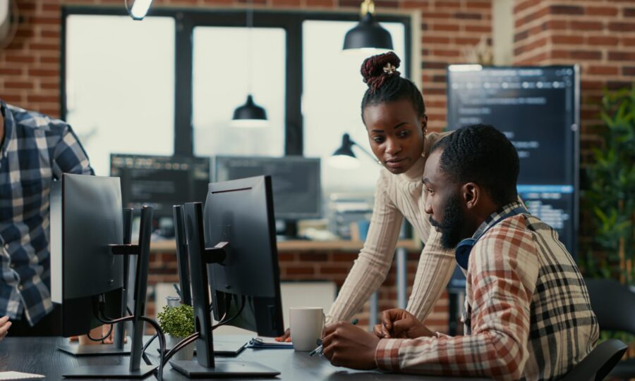 Two people looking at a computer screen on a desk