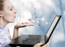 woman blowing hearts and kisses at a laptop screen