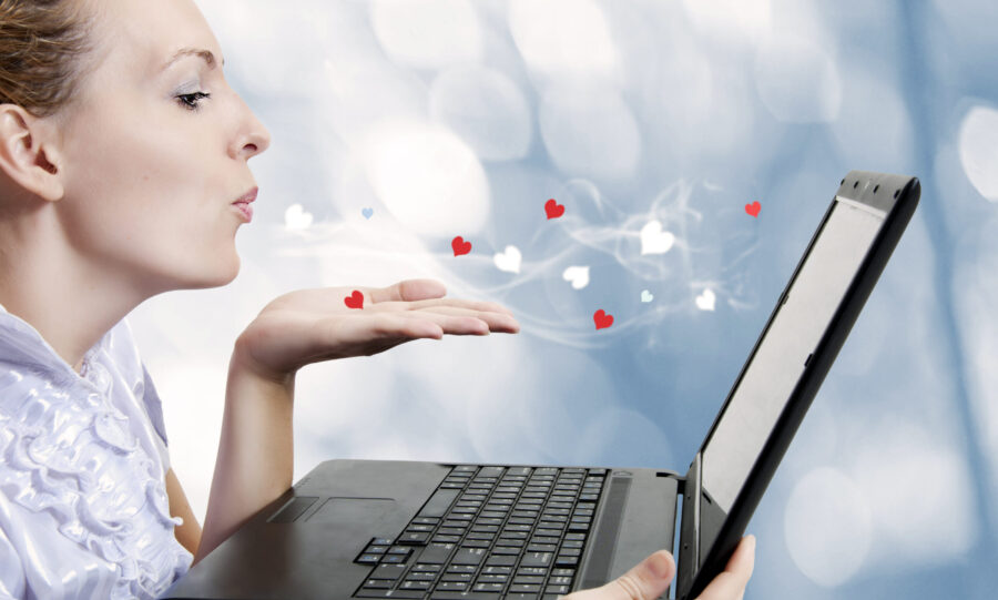 woman blowing hearts and kisses at a laptop screen