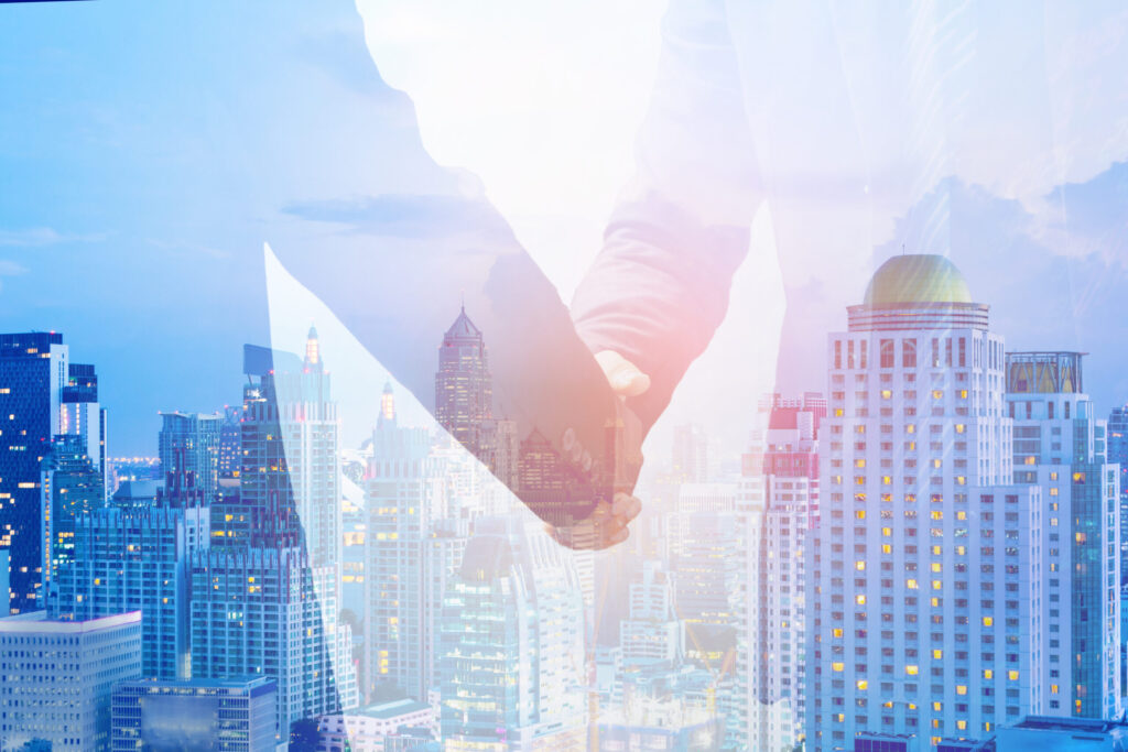 Partners shake hands over a cityscape backdrop